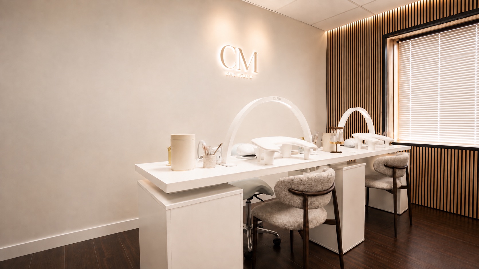 De nagelstudio van CM Beauty in Voorburg, met verlicht CM-logo boven de manicuretafels
